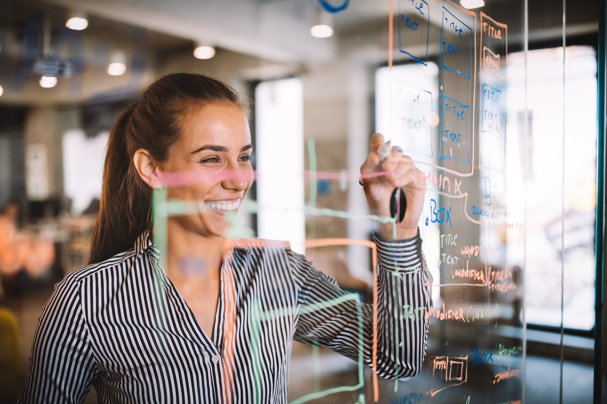 Woman working and writing on the glass board in office. Business, technology, research concept